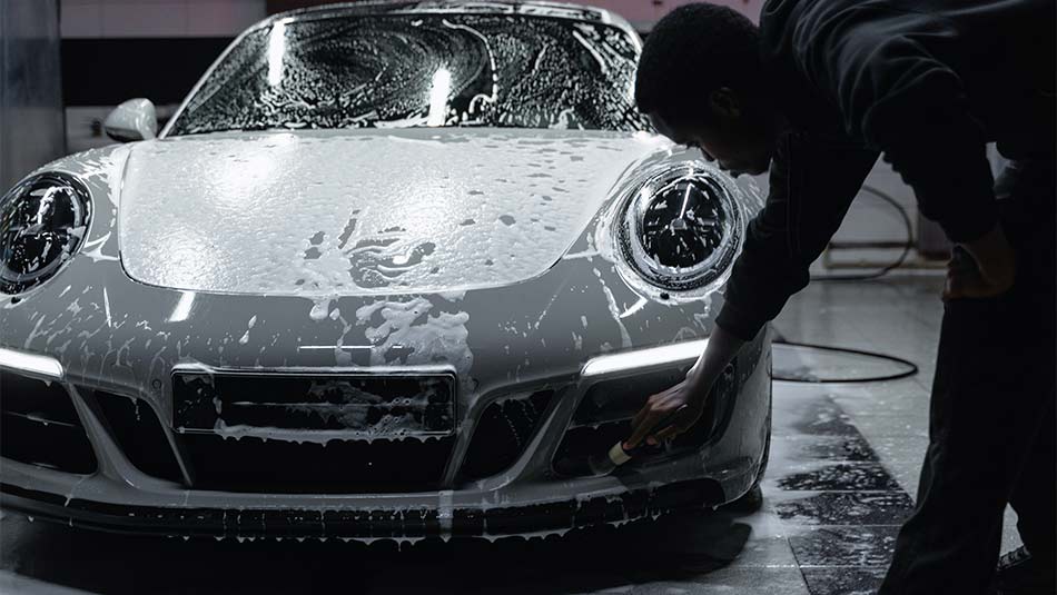 man washing a car using a detail brush