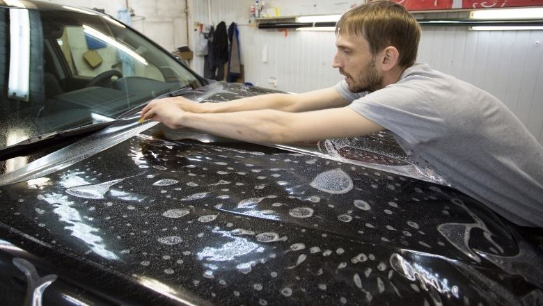 guy applying paint protection film to a car