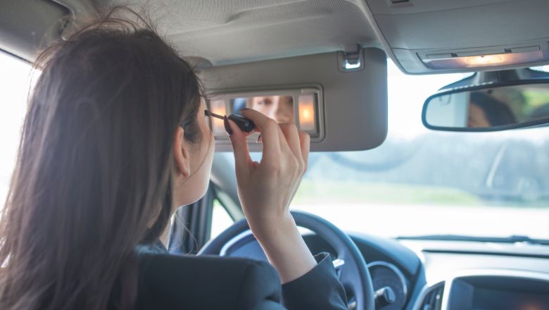 woman applying eyelash serum in the car